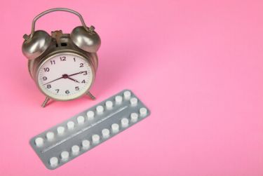 A packet of contraceptive pills with an alarm clock