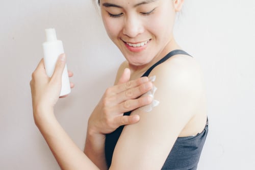 Woman applying moisturiser to treat her psoriasis